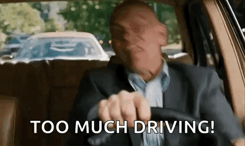 A Man In A Suit Is Driving A Car And Making A Face . GIF