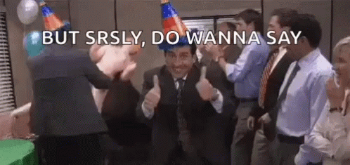 A Man In A Suit Is Giving A Thumbs Up At A Party While Wearing A Party Hat . GIF