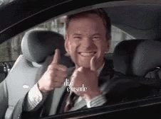 a man in a suit is giving a thumbs up in a car