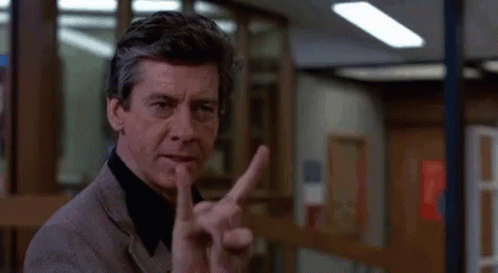 a man in a suit is giving the middle finger in a room .