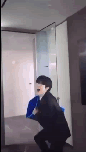 A Man In A Suit Is Holding A Blue Umbrella While Standing In A Hallway . GIF