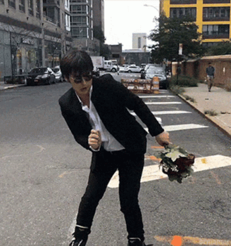 A Man In A Suit Is Holding A Bouquet Of Flowers In His Hand GIF