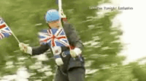 A Man In A Suit Is Holding A British Flag In His Hands . GIF
