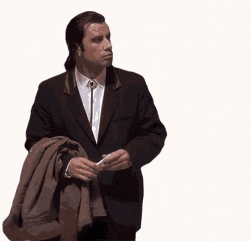A Man In A Suit Is Holding A Brown Jacket GIF