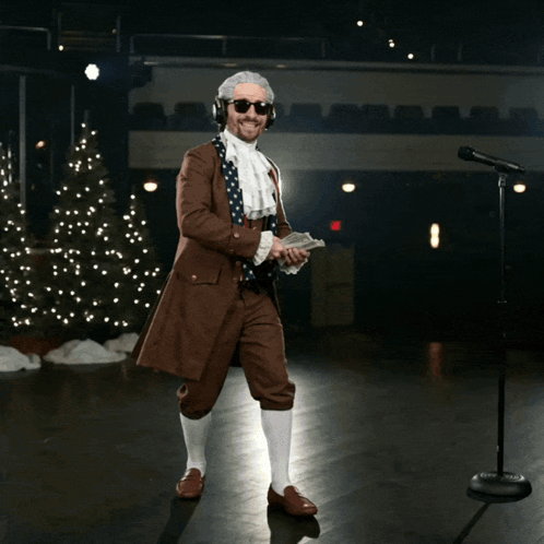 A Man In A Suit Is Holding A Bunch Of Money In Front Of A Christmas Tree GIF