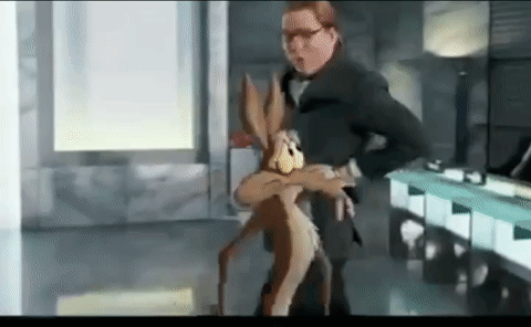 a man in a suit is holding a cartoon rabbit in his arms in a room .