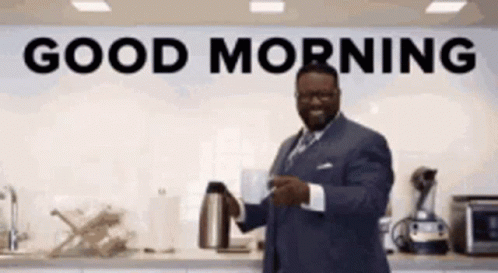 A Man In A Suit Is Holding A Cup Of Coffee In Front Of A Sign That Says Good Morning . GIF