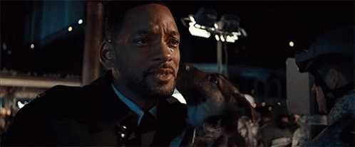 a man in a suit is holding a dog in his arms .