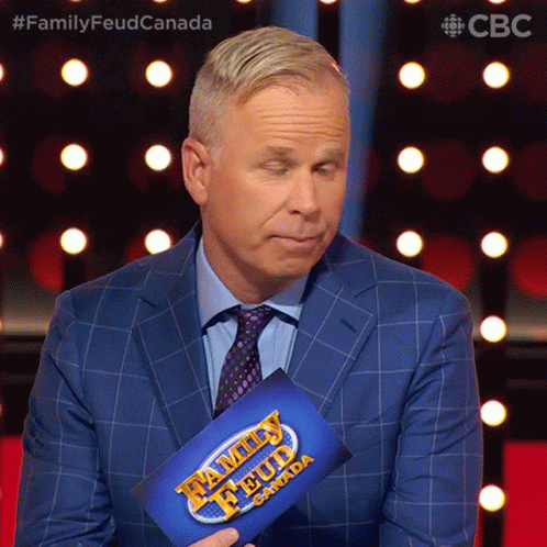 A Man In A Suit Is Holding A Family Feud Canada Sign GIF