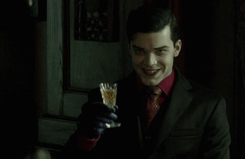 A Man In A Suit Is Holding A Glass In His Hand GIF