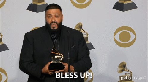 A Man In A Suit Is Holding A Grammy Trophy And Says Bless Up GIF