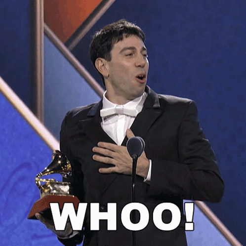A Man In A Suit Is Holding A Grammy Trophy And Says Whoo GIF