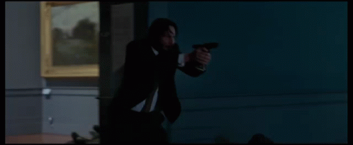 a man in a suit is holding a gun in front of a statue