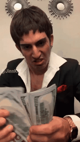 A Man In A Suit Is Holding A Large Stack Of Money GIF