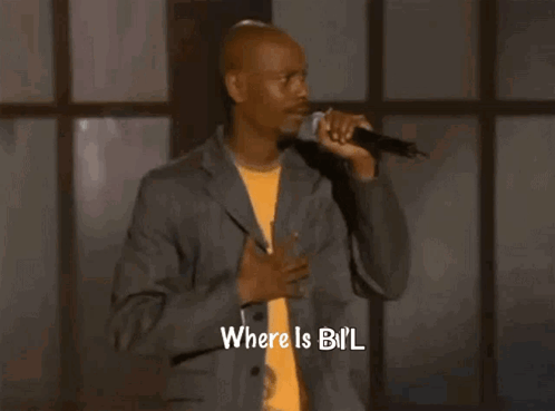 a man in a suit is holding a microphone and saying where is bil .