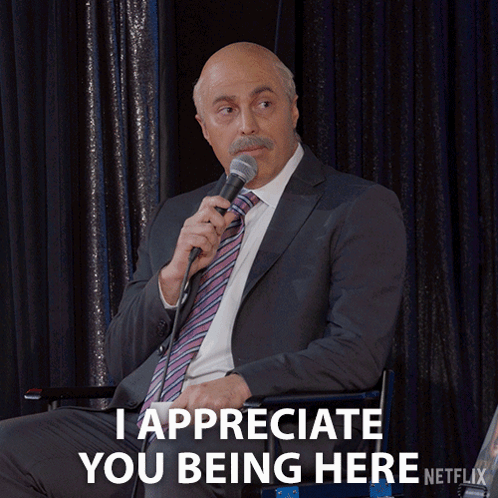 A Man In A Suit Is Holding A Microphone And Says I Appreciate You Being Here GIF