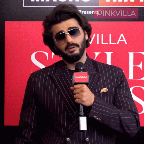 A Man In A Suit Is Holding A Microphone That Says Pinkvilla On It GIF
