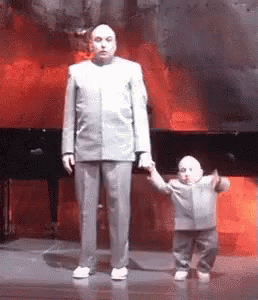 A Man In A Suit Is Holding A Small Child 'S Hand . GIF