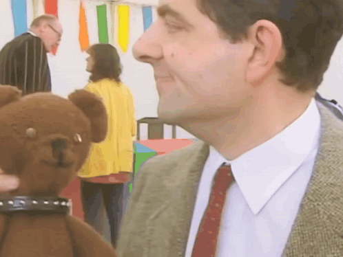 A Man In A Suit Is Holding A Teddy Bear GIF