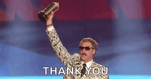 A Man In A Suit Is Holding A Trophy In His Hand And Saying Thank You . GIF
