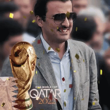 A Man In A Suit Is Holding A Trophy That Says Qatar 2022 GIF