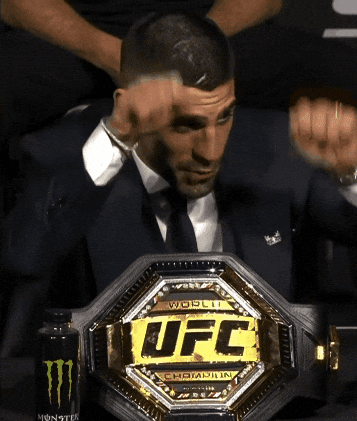 A Man In A Suit Is Holding A Ufc Belt GIF