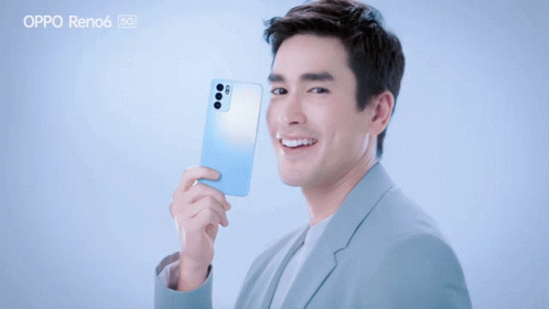 A Man In A Suit Is Holding An Oppo Reno6 GIF