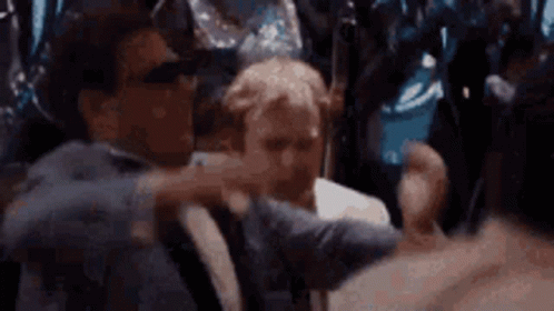 A Man In A Suit Is Holding Another Man 'S Arm In A Crowd Of People . GIF