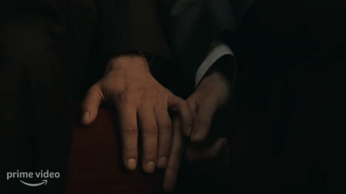 A Man In A Suit Is Holding Another Man 'S Hand In A Dark Room With A Prime Video Logo In The Corner GIF