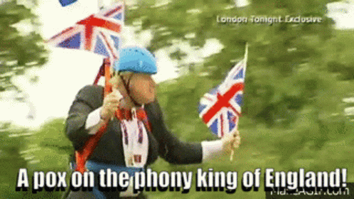 A Man In A Suit Is Holding British Flags And Says " A Pox On The Phony King Of England ! " GIF