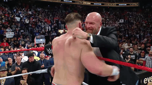 A Man In A Suit Is Hugging Another Man In A Ring GIF