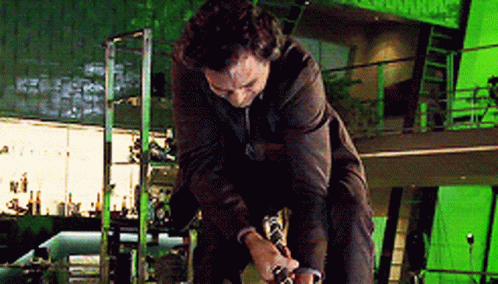 A Man In A Suit Is Kneeling Down In Front Of A Green Screen . GIF