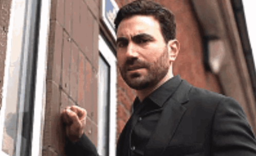 A Man In A Suit Is Knocking On A Door With His Fist . GIF