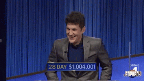 A Man In A Suit Is Laughing While Playing A Game Of Jeopardy GIF