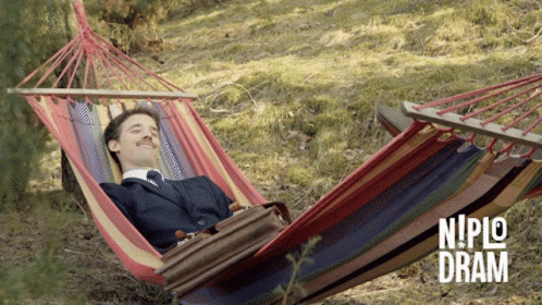 A Man In A Suit Is Laying In A Hammock With Niplo Dram Written On The Bottom Right GIF
