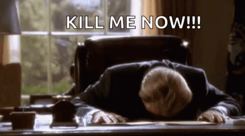 A Man In A Suit Is Laying On A Desk With His Head On The Desk And The Words `` Kill Me Now '' Written Above Him . GIF