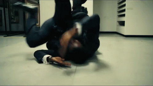 A Man In A Suit Is Laying On The Floor In A Room . GIF