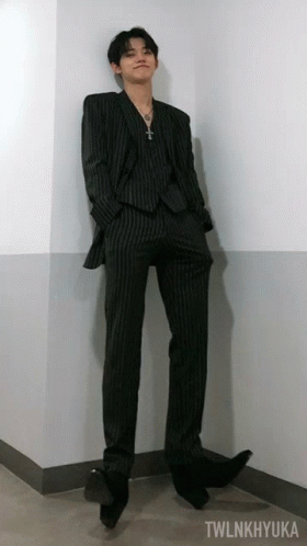 A Man In A Suit Is Leaning Against A Wall With Twlnkhyuka Written On The Bottom GIF