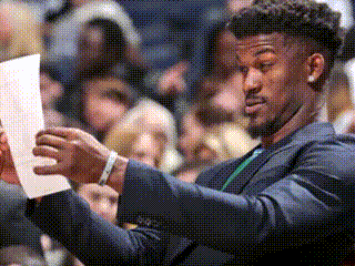 A Man In A Suit Is Looking At A Piece Of Paper . GIF