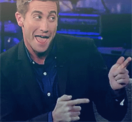A Man In A Suit Is Making A Face And Pointing At Something GIF