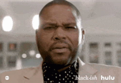 A Man In A Suit Is Making A Funny Face . GIF
