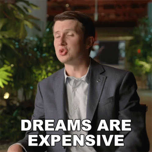 A Man In A Suit Is Making A Funny Face With The Words Dreams Are Expensive Behind Him GIF