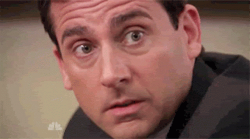 A Man In A Suit Is Making A Surprised Face . GIF