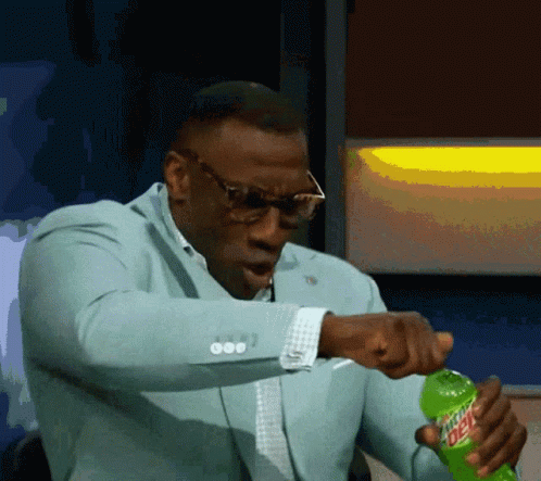 A Man In A Suit Is Opening A Bottle Of Mtn Dew GIF