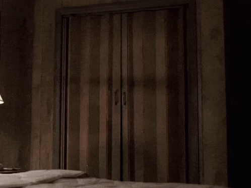 a man in a suit is peeking out of a doorway