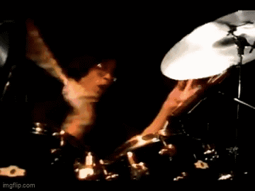 A Man In A Suit Is Playing A Guitar On Stage . GIF