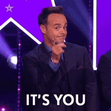 A Man In A Suit Is Pointing At The Camera With The Words It 'S You Behind Him GIF
