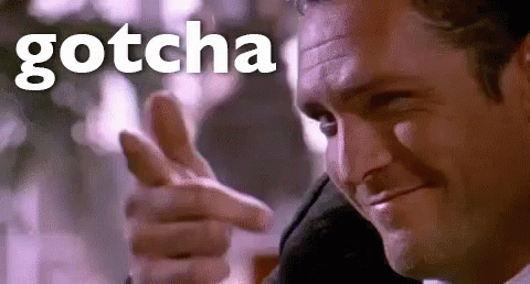 A Man In A Suit Is Pointing His Finger At The Camera With The Word Gotcha Behind Him . GIF