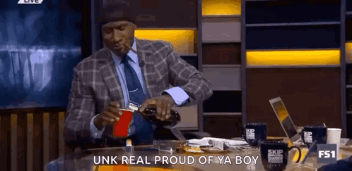 A Man In A Suit Is Pouring A Drink Into A Red Cup GIF