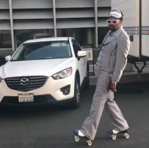 A Man In A Suit Is Rollerblading In Front Of A Mazda GIF